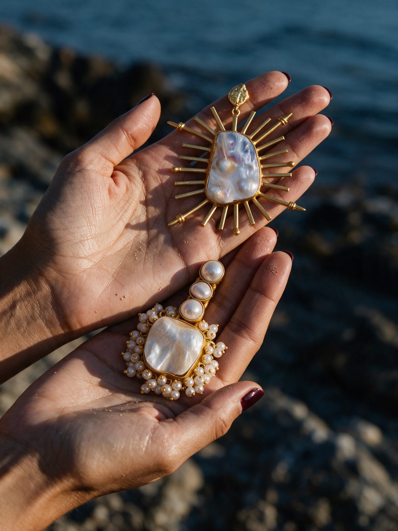 Two hands holding a sunburst earring and a pearl cluster earring