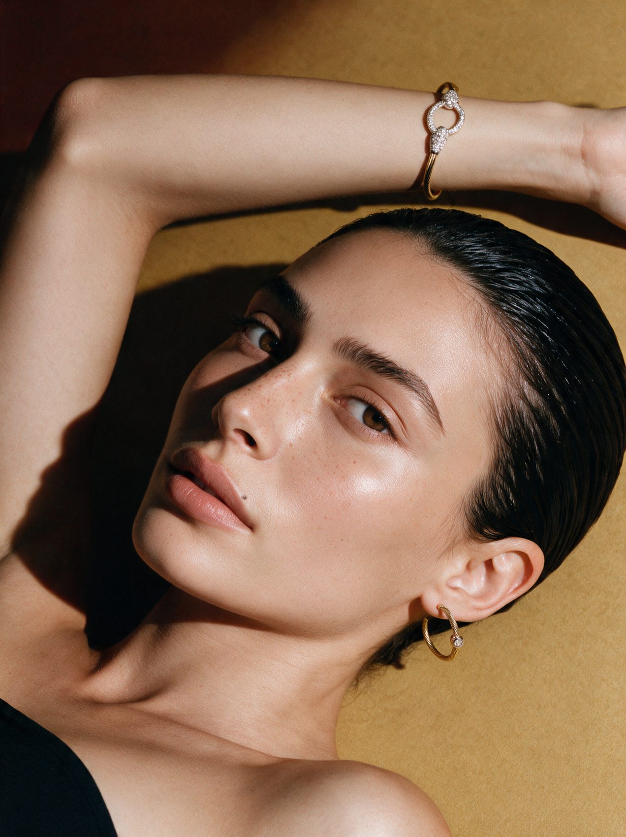 Model lying back with a pavé cuff on her raised arm
